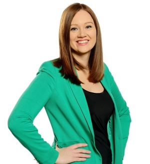 Jessica Rusnak wears a bright green blazer and black tank top, standing with her hands on her hips