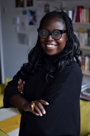Eunice Bélidor smiles for the camera, arms crossed, wearing a black tunic