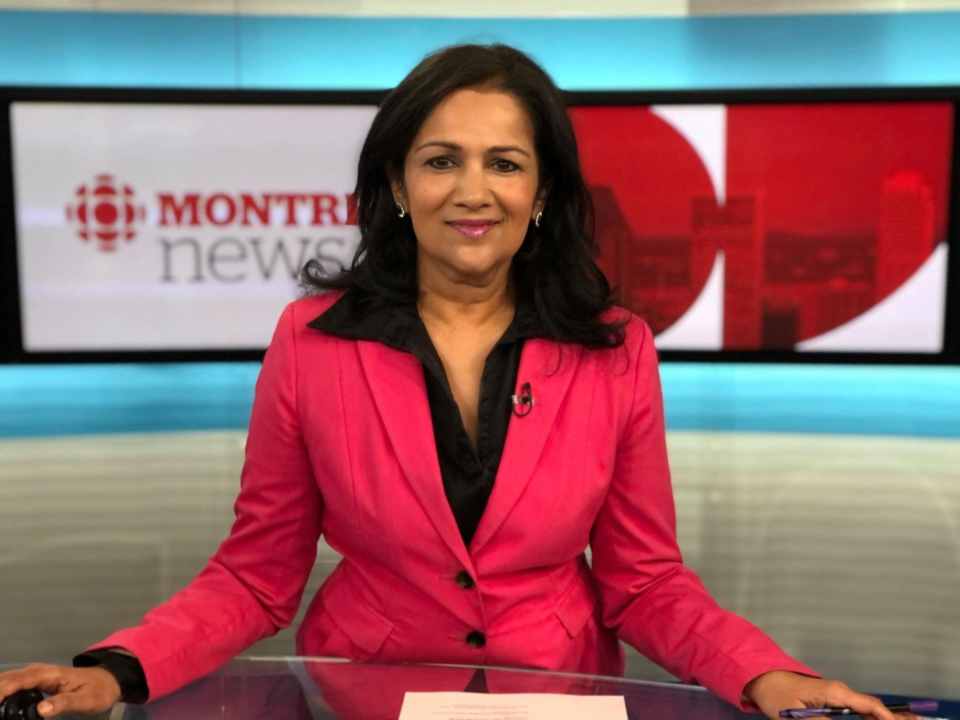 Sudha Krishnan sits behind the anchor desk.