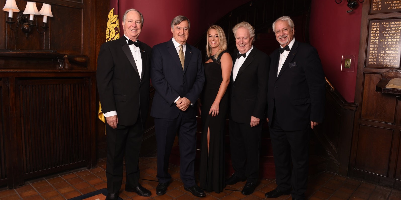 Julie Quenneville in a black evening dress stands beside politicians