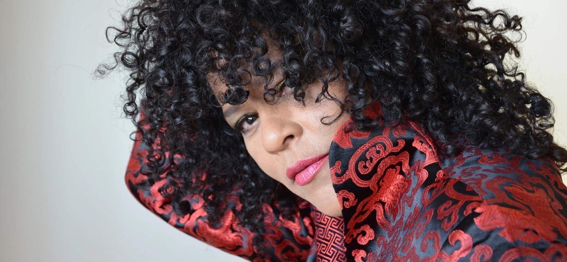 Dawn Tyler Watson, wearing a red brocade jacket.