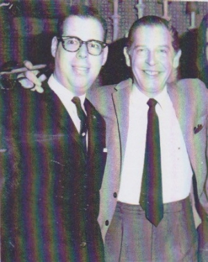 vintage black and white photo of David Leonard smiling beside Milton Berle, who holds a cigar, with his arm around Leonard.