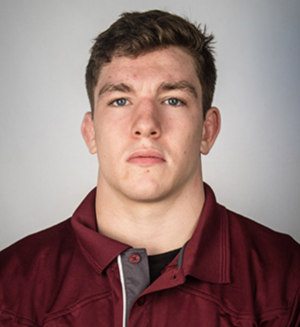 Alexander Moore wears a maroon warm-up jacket