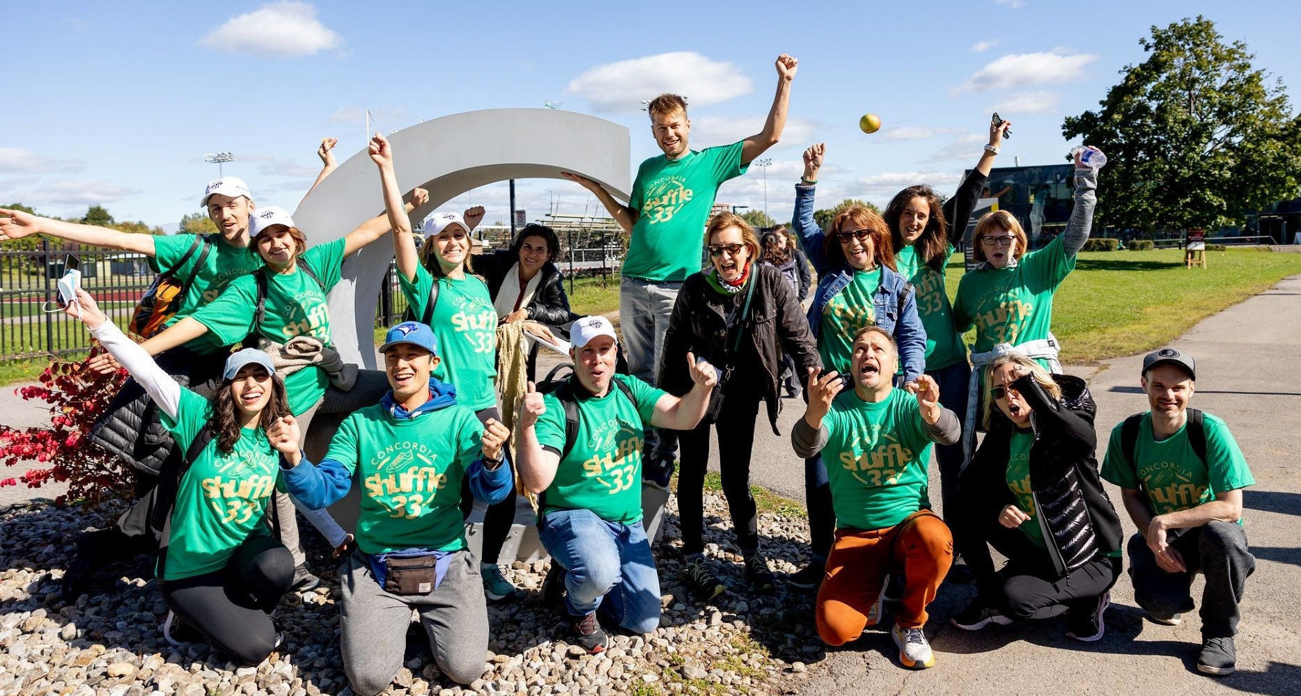 A group of excited people wearing green Shuffle T-shirts gather at Loyola Campus. 