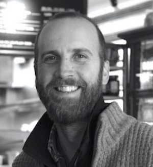 Black and white image of a bearded man wearing a knit cardigan