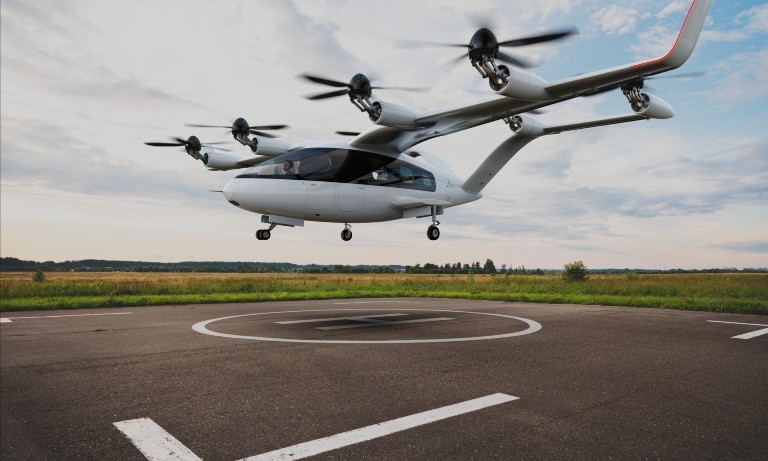 A simulated image of an electric aircraft hovering over a landing pad