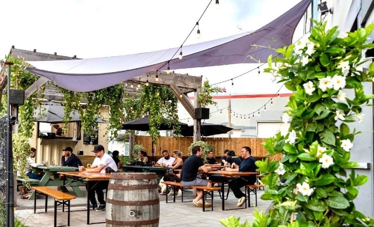 People sit at wooden tables on an outdoor terrace in Montreal