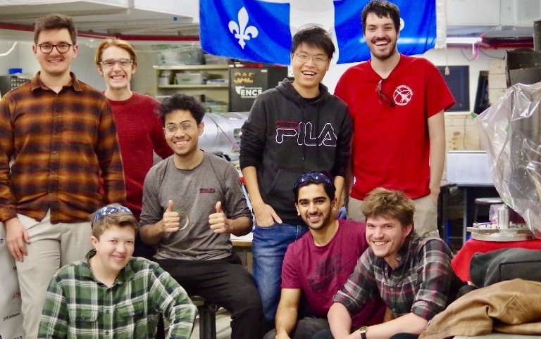Eight students group together in the Space Concordia workspace in the basement of the Henry F. Hall Building