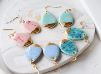 Four sets of coloured teardrop earrings on a marble plate