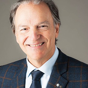 A smiling man wears a checkered suit and dark tie