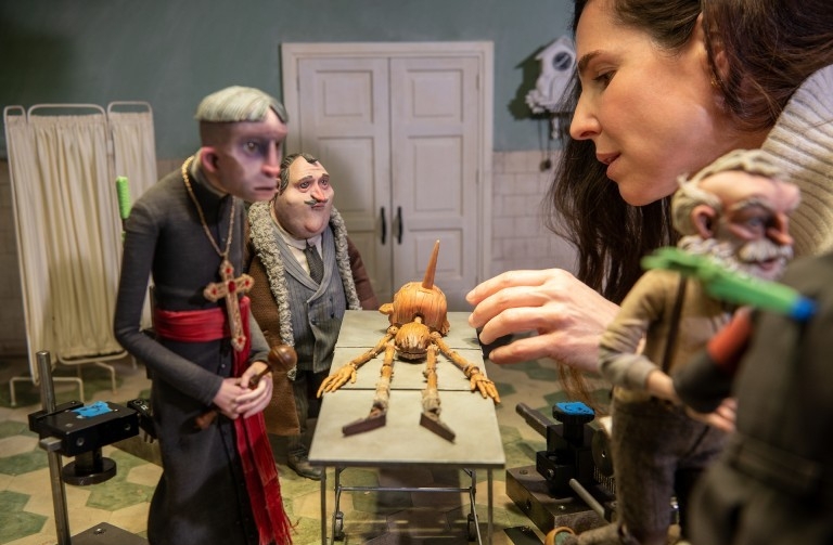 A woman adjusts a stop-motion figure on the set of Guillermo del Toro's Pinocchio