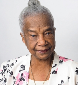 Woman with white hair in a bun, wearing flowered blazer