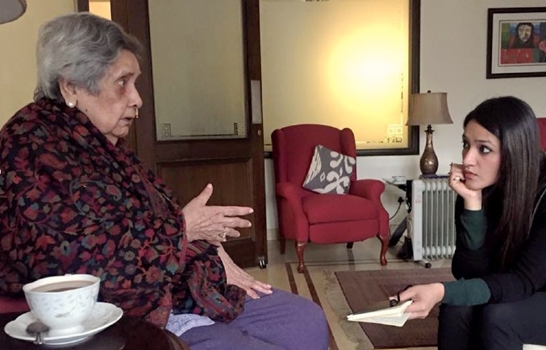 Two women sit and have a conversation with a tea cup in the foreground