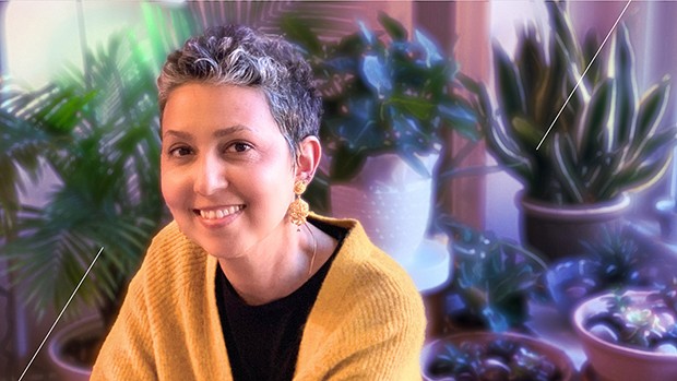 Nadia Chaudhri portrait of woman smiling, wearing a yellow cardigan