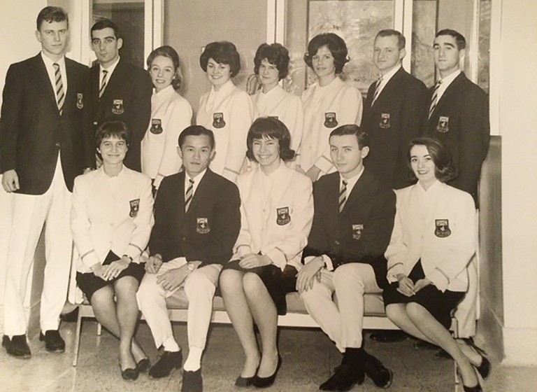 A sepia tone image of a group of students who wear blazers with a crest. The women wear white ones and the men wear dark ones