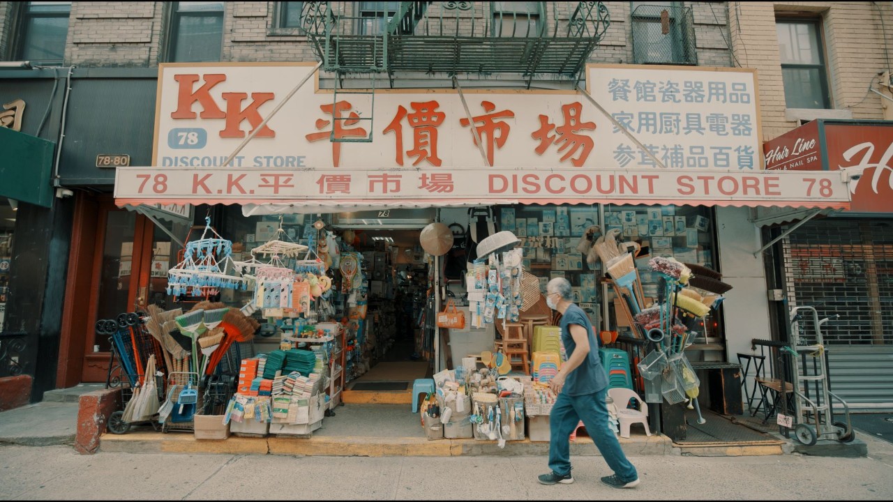 Photo of a man waking in front of a storefront in Chinatown