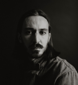 Black and white portrait of a man with long hair wearing a button-up shirt