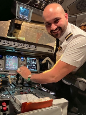 Portrait of a man wearing a pilot's uniform at the controls of an aircraft