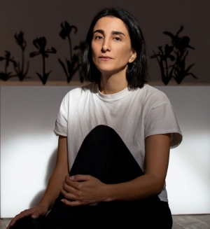 Portrait of a woman with dark hair, wearing a white T-shirt