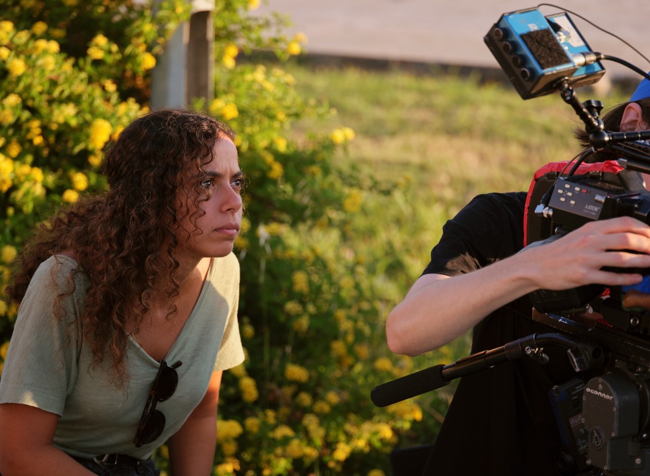 Joyce Joumaa crouches and looks intently as a camera operator is filming