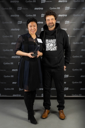 Mishel Wong, wearing a black dress and boots, at the Grand Prix Dux Gala, accompanied by her director of operations at Bo.