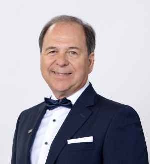 Portrait of a man smiling at the camera, wearing a black blazer over a white dress shirt and black bow tie