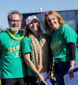 Image of two women and a man posing outside in matching green t-shirts