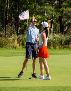 A man and a woman give each other a high five on a golf green 