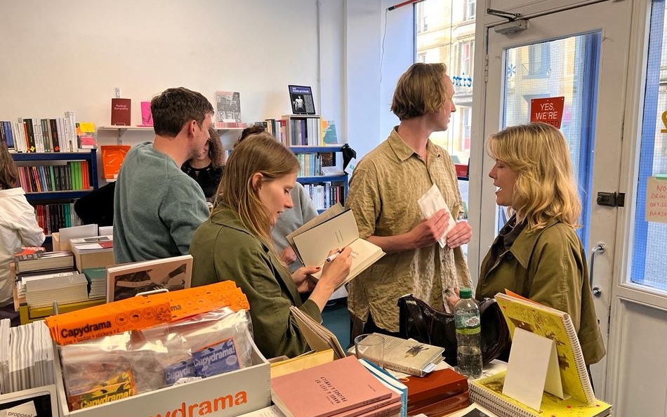 A woman signs copies of her books for people in a bookstore in Glasgow, Scotland