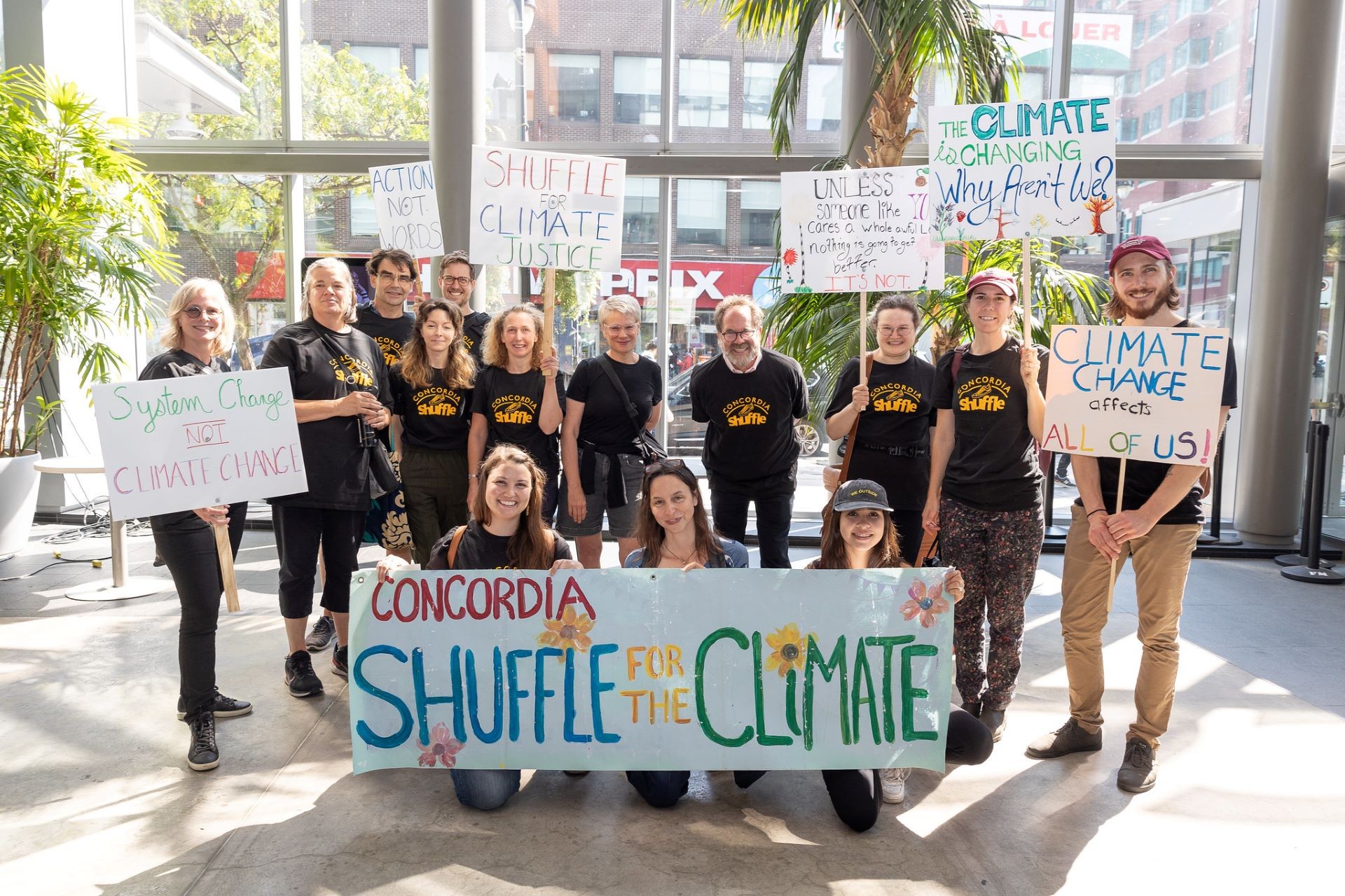 Group of people in black t-shirts holding signs.