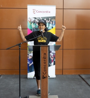 A woman in a baseball cap and black clothing at a podium.