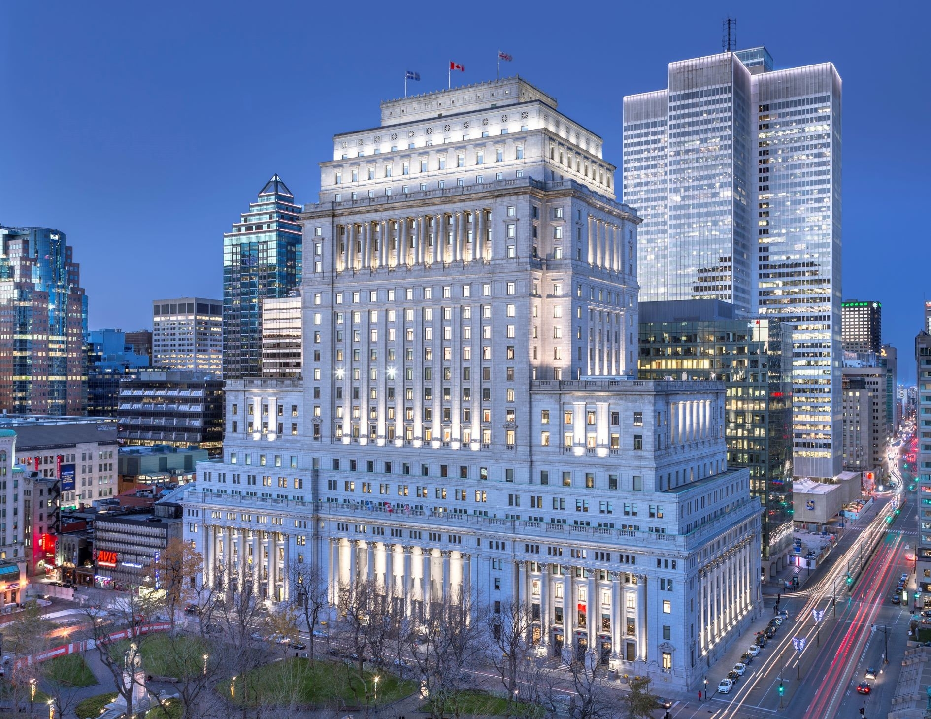 Aerial photograph capturing the Sun Life Building in Montreal at dusk. The building stands out with its grand, historical architecture amidst the modern cityscape, showcasing a blend of classic and contemporary structures.