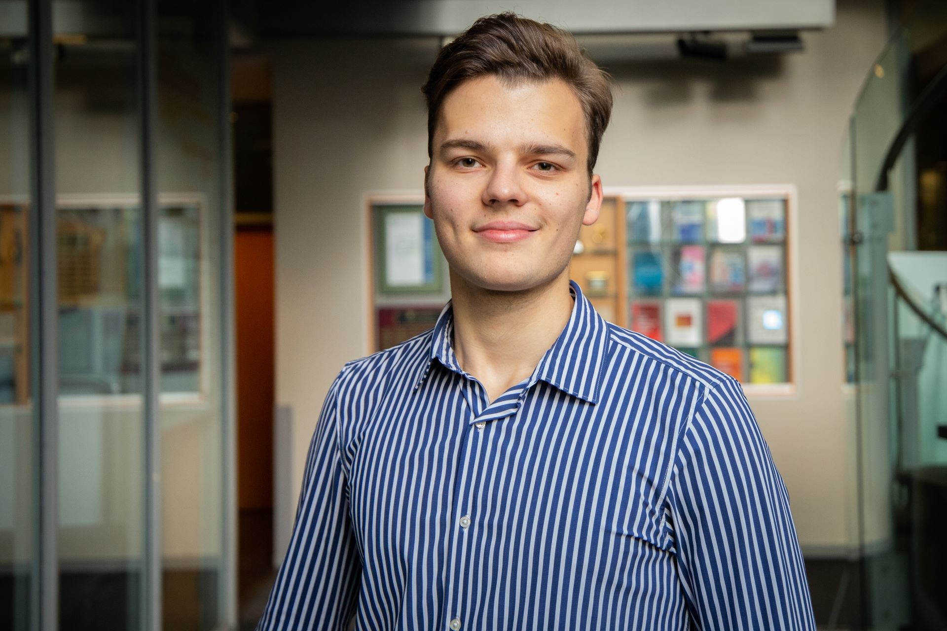 Bogdan wears a blue, striped button-up shirt, and has short dark hair.