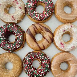 Rows of beige-coloured doughnuts topped with different coloured icing and sprinkles