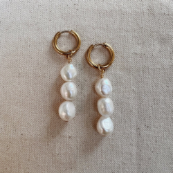 A pair of gold earrings, each with three pearls hanging from them vertically