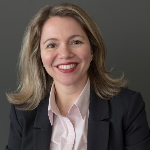 Portrait of a smiling woman with straight, shoulder-length blonde hair wearing a business suit.