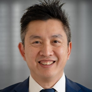 Portrait of a smiling man with close-cropped black hair wearing a business suit.