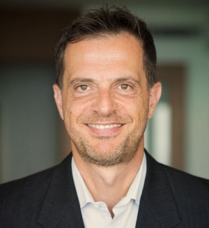 Portrait of a smiling man wearing a shirt and suit jacket.