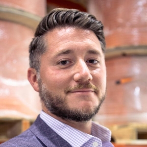 Portrait of a smiling man with close-cropped brown hair and a beard wearing a business suit.