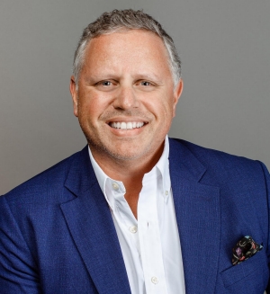 Portrait of a man wearing a blue suit jacket and white shirt.