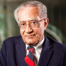 An man with gray hair and glasses, wearing a navy blazer and a red and green striped tie.