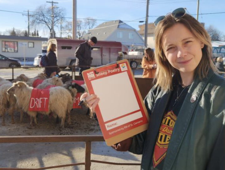 Image of a smiling woman in a leather jacket and sunglasses a top her head holding a clipboard with Sheep Poetry printed on it.