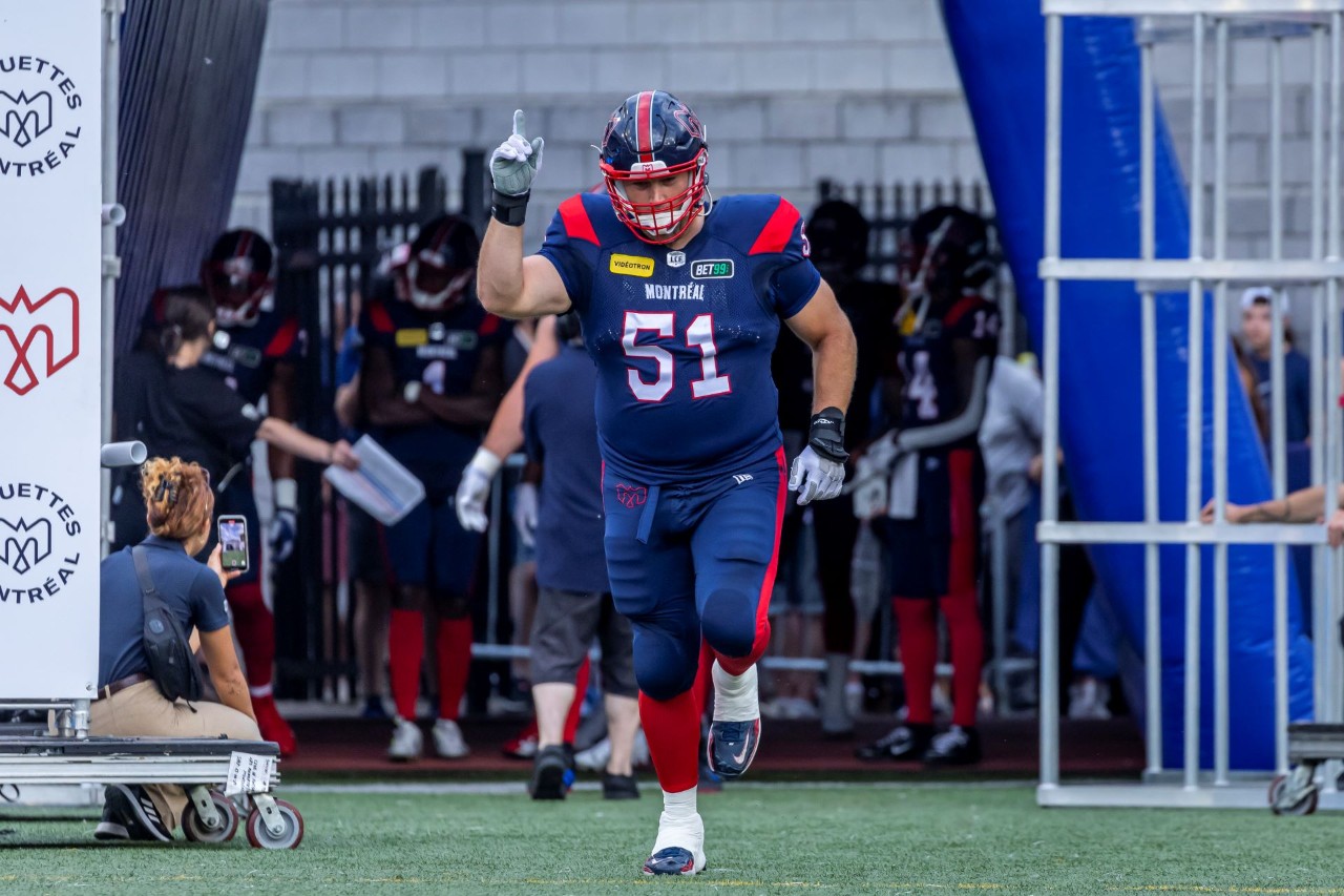 A football player dressed in uniform with the number 51 on his jersey runs onto a field