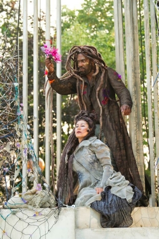 Two people dressed in costumes pose for an image in a wooded area.