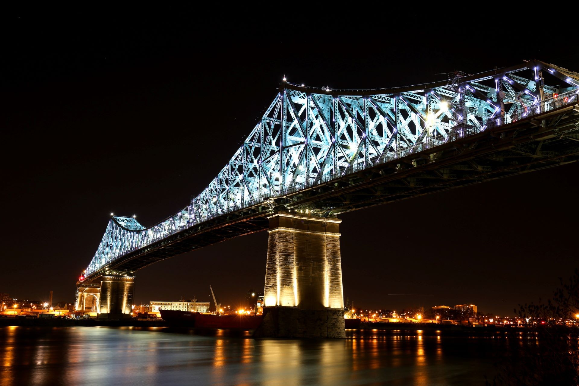 The Jacques Cartier Bridge lit up at night with a dynamic light installation.