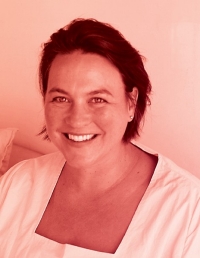 Woman with short, dark, straight hair that is pushed back wears a light top with a square neckline and smiles at the camera