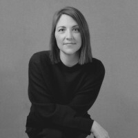 A woman with shoulder length hair sits cross armed for a black and white portrait.