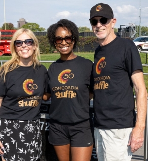 Three individuals stand next to one another, all wearing black Shuffle t-shirts.