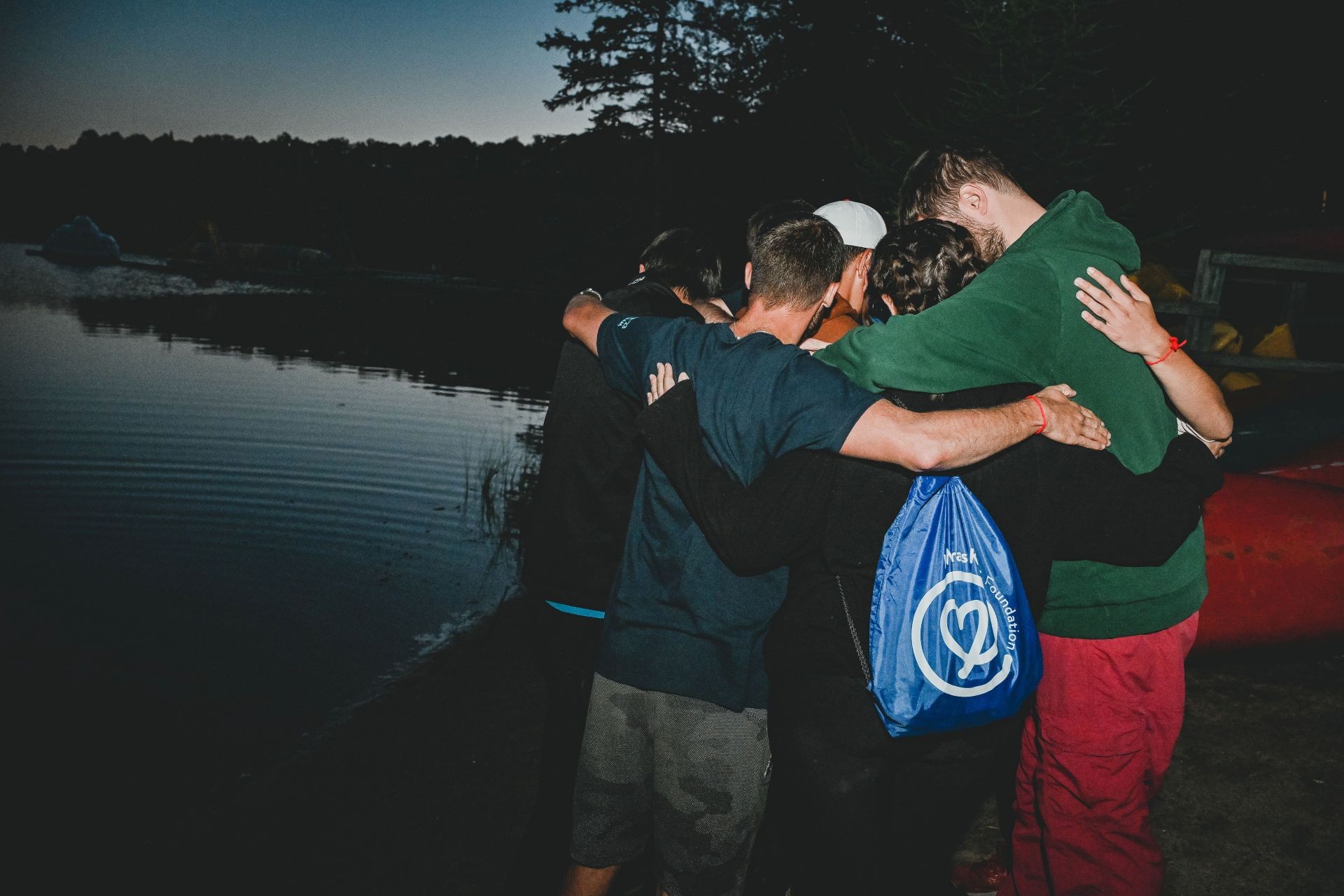Myra’s Kids Foundation’s first three-day weekend grief camp A group of kids stand huddled in front of a lake at dusk