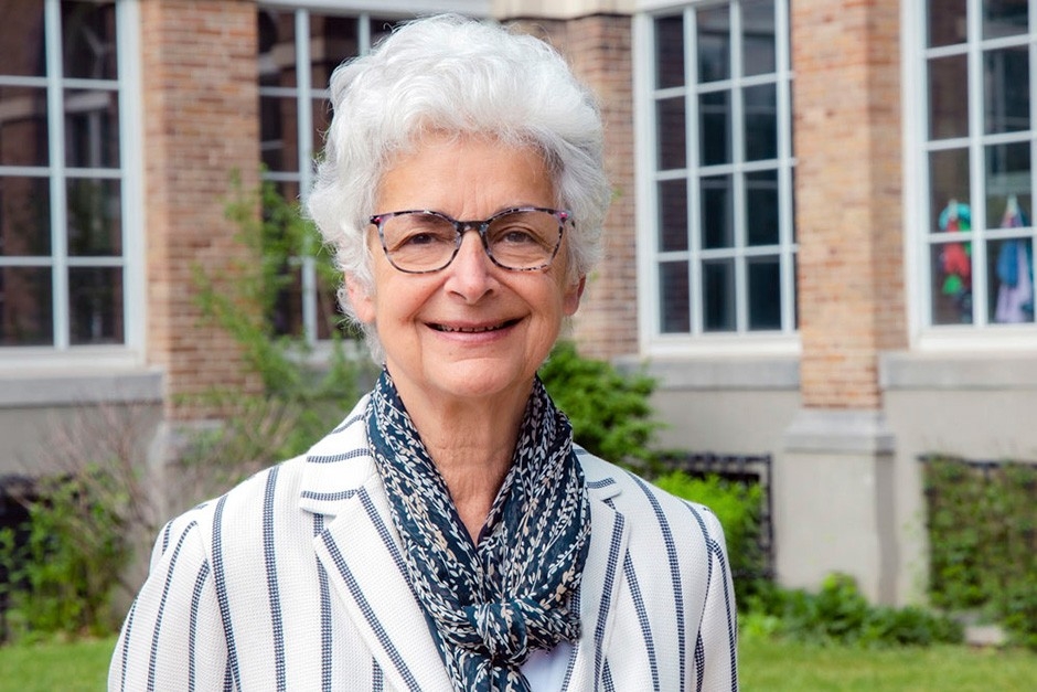 Corinne Charette Corinne has white hair, glasses and is wearing a white jacket with navy stripes.